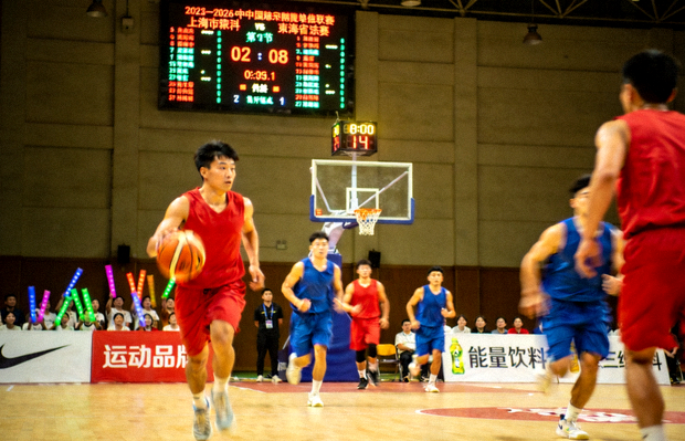 篮球馆内进行中的职业篮球比赛，球员在场上跑位进攻